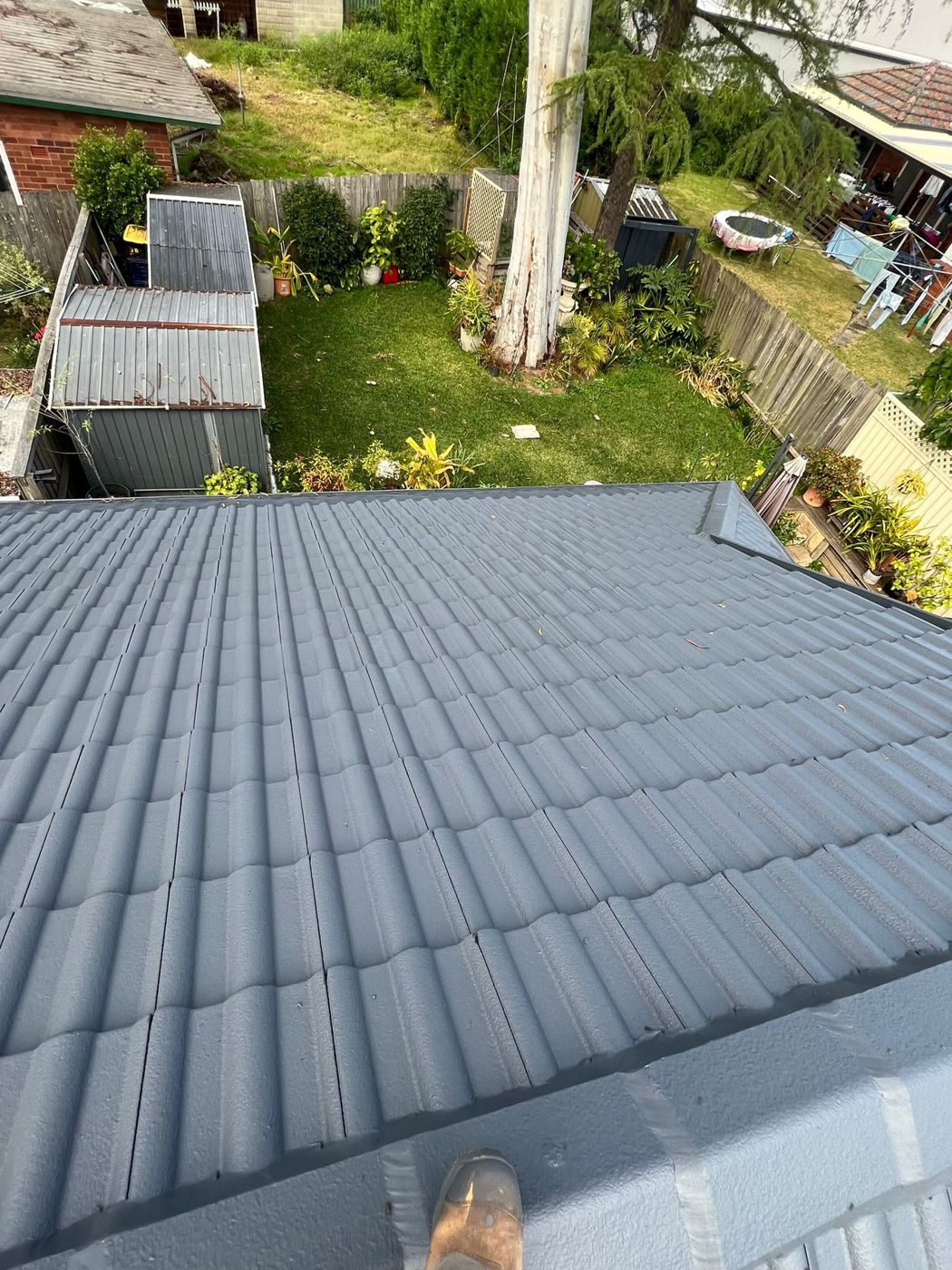 A roof freshly recoated in charcoal grey under a clear sky
